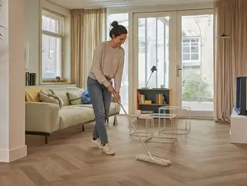 Vrouw reinigt een Novilon vinylvloer met een Swiffer voor eenvoudig onderhoud en een langdurig mooie vloer.